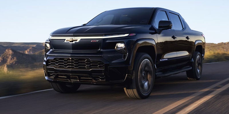 2023 Chevrolet Silverado EV driving along a winding mountain road.